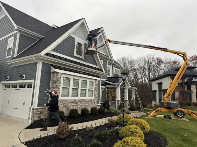 The GrimeBusters Soft Wash and Holiday Lighting Team of Three Installs Christmas Holiday Lights on a Two Story, Gray Suburban Home in Erie.