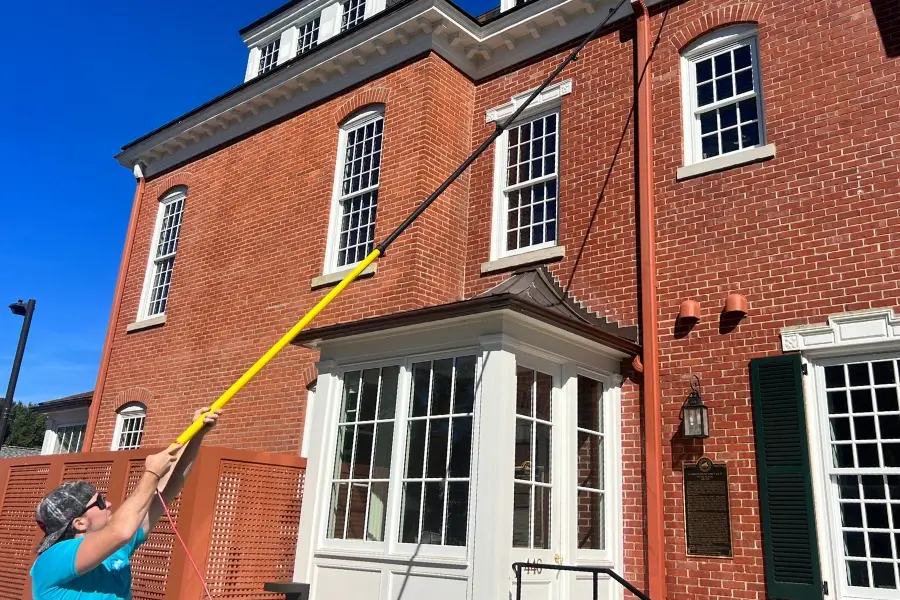 A GrimeBusters Soft Wash and Holiday Lighting Team Member Washes a Commercial Building's Windows in Pittsburgh.